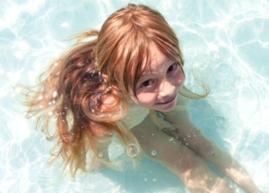 Kind sitzt im seichten Poolwasser