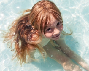 Kleinkind sitzt im seichten Poolwasser