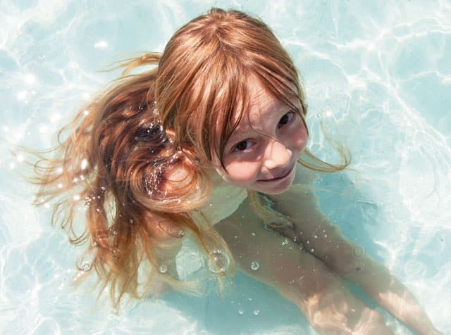 Kleinkind sitzt im seichten Poolwasser