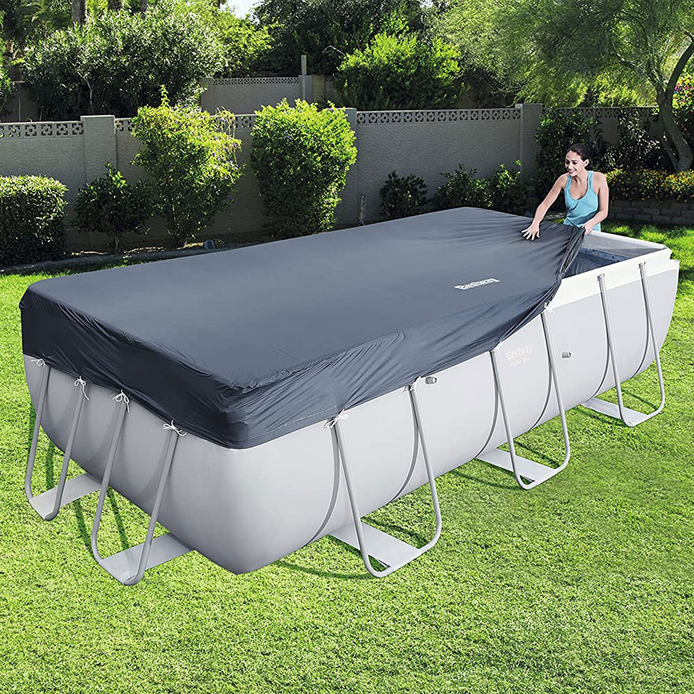 Frau spannt die Flowclear™ PVC-Abdeckplane, 396 x 185 cm, für eckige 412 x 201 und 404 x 201 cm Power Steel™ Pools, über ihren Pool