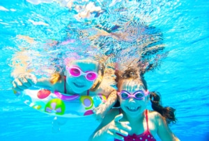 Kinder freuen sich unter Wasser im Pool