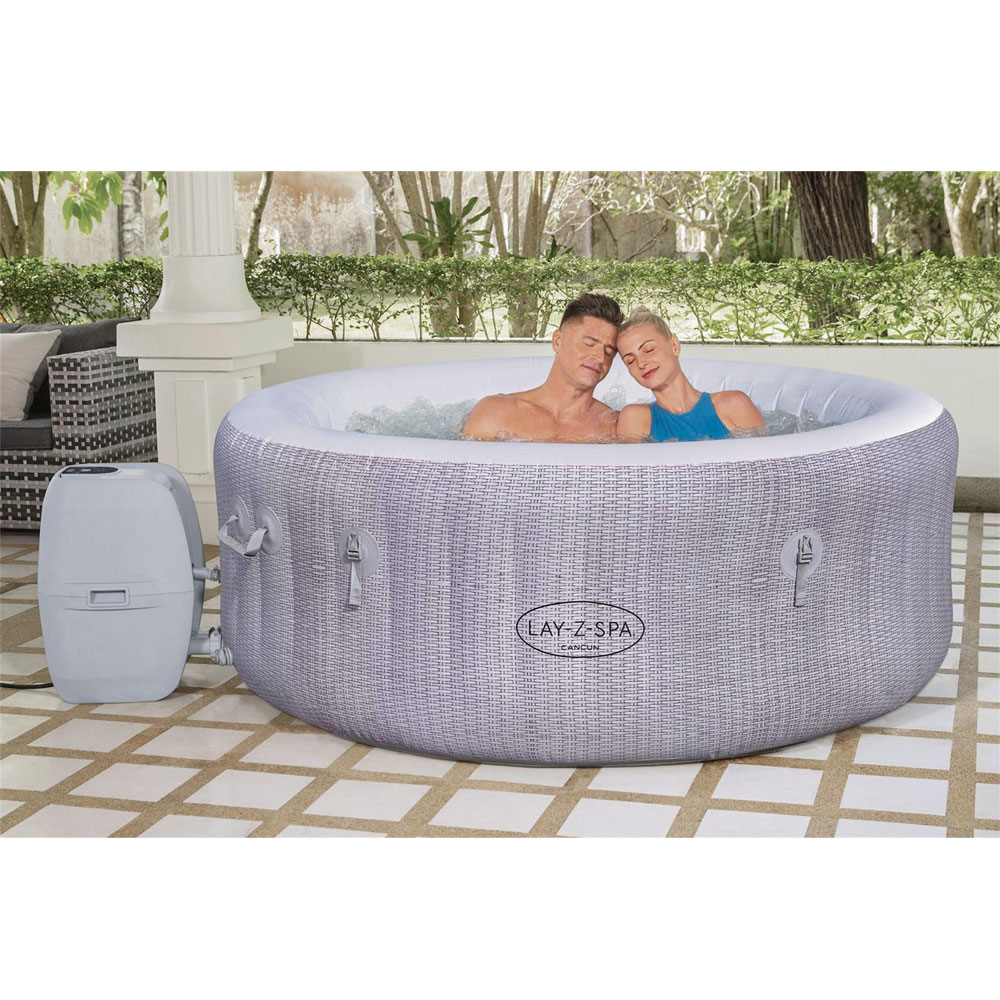 zwei Menschen entspannen sich im LAY-Z-SPA® Cancun AirJet™ Whirlpool, 180 x 66 cm, 2-4 Personen, rund, rosenweiße Rattan-Optik