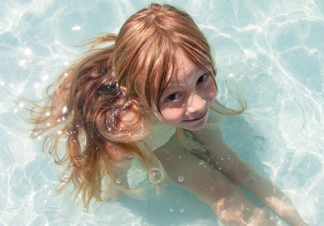 Kleines Kind sitzt im Poolwasser