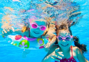 Kinder spielen und lachen im Pool unter Wasser