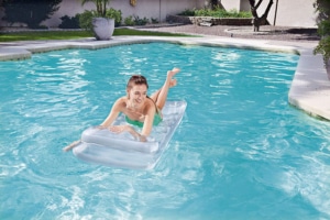 Frau entspannt sich auf ihrer Luftmatratze im Pool