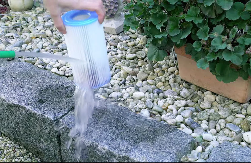 Filterkartusche wird mit Gartenschlauch gereinigt